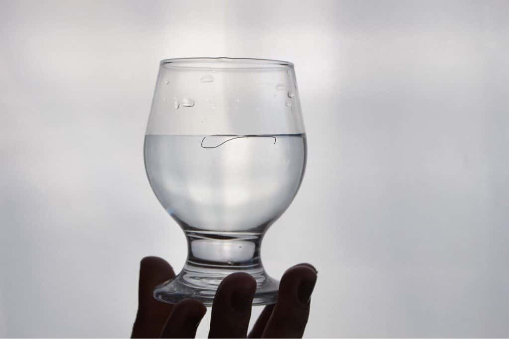 Copo de vidro com fio dentro no boiando no copo