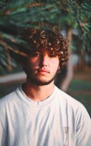 Homem de cabelo ondulado, com corte repicado
