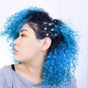 mulher de perfil com cabelo azul e raiz preta